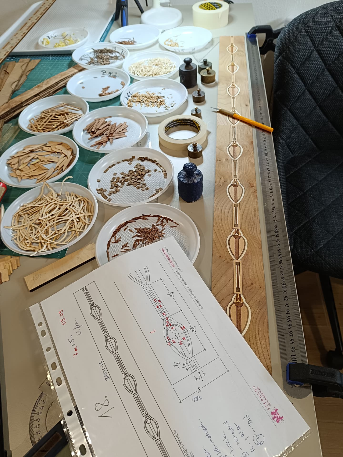 Marquetry design drawing and veneer samples on the workbench